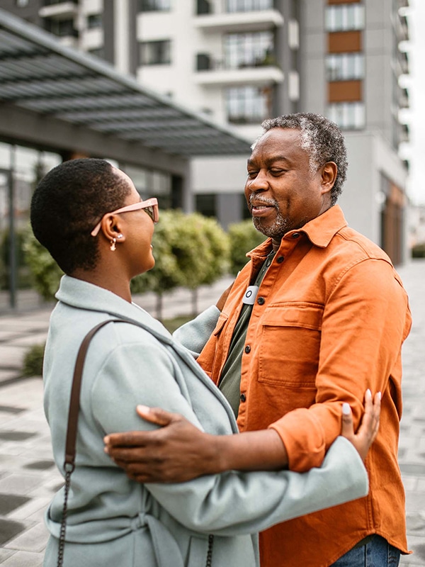 Man wearing Medical Alert's Mini Mobile System pendant embracing loved one